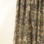 Tessuto decorativo ispirato a scene esotiche, raffigurante donne in abiti tradizionali immerse in una lussureggiante foresta tropicale con cascate, alberi imponenti e vegetazione rigogliosa. I toni caldi del verde, marrone e ocra creano un design ricco e suggestivo, ideale per arredamenti etnici, tende, cuscini e decorazioni d'interni in stile tropicale.