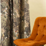 Tessuto decorativo ispirato a scene esotiche, raffigurante donne in abiti tradizionali immerse in una lussureggiante foresta tropicale con cascate, alberi imponenti e vegetazione rigogliosa. I toni caldi del verde, marrone e ocra creano un design ricco e suggestivo, ideale per arredamenti etnici, tende, cuscini e decorazioni d'interni in stile tropicale.