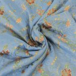 Lampasso fabric with light blue background and woven floral pattern in classic style. Flowers in shades of red, orange and yellow with green leaves, perfect for curtains, pillows, upholstery and shabby chic decorations. Elegant and vibrant print for decorating with personality. Made in Italy.