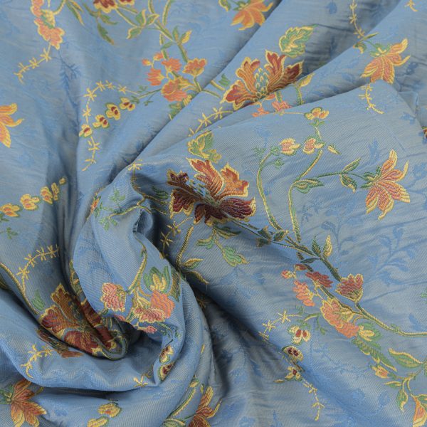 Lampasso fabric with light blue background and woven floral pattern in classic style. Flowers in shades of red, orange and yellow with green leaves, perfect for curtains, pillows, upholstery and shabby chic decorations. Elegant and vibrant print for decorating with personality. Made in Italy.