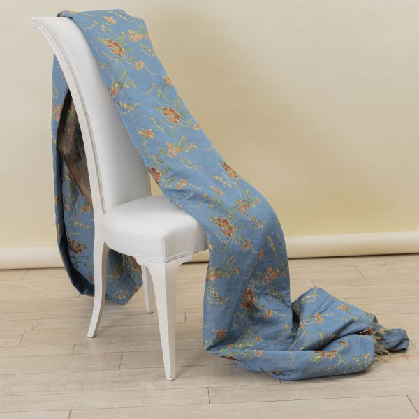 Lampasso fabric with light blue background and woven floral pattern in classic style. Flowers in shades of red, orange and yellow with green leaves, perfect for curtains, pillows, upholstery and shabby chic decorations. Elegant and vibrant print for decorating with personality. Made in Italy.