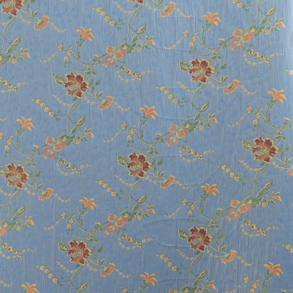 Lampasso fabric with light blue background and woven floral pattern in classic style. Flowers in shades of red, orange and yellow with green leaves, perfect for curtains, pillows, upholstery and shabby chic decorations. Elegant and vibrant print for decorating with personality. Made in Italy.