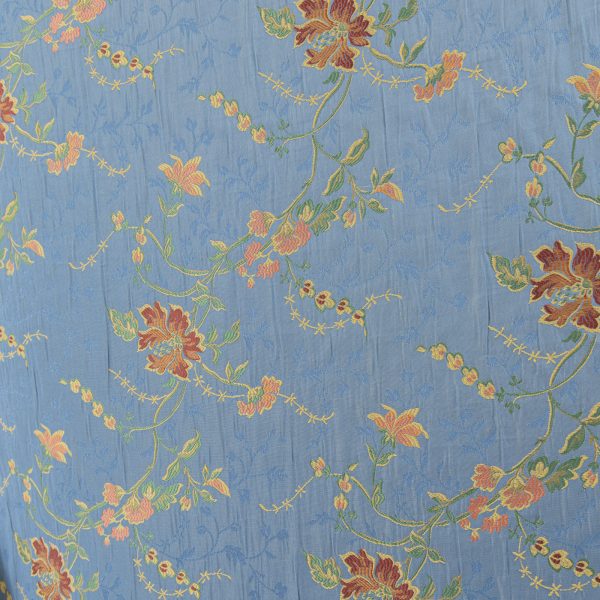 Lampasso fabric with light blue background and woven floral pattern in classic style. Flowers in shades of red, orange and yellow with green leaves, perfect for curtains, pillows, upholstery and shabby chic decorations. Elegant and vibrant print for decorating with personality. Made in Italy.