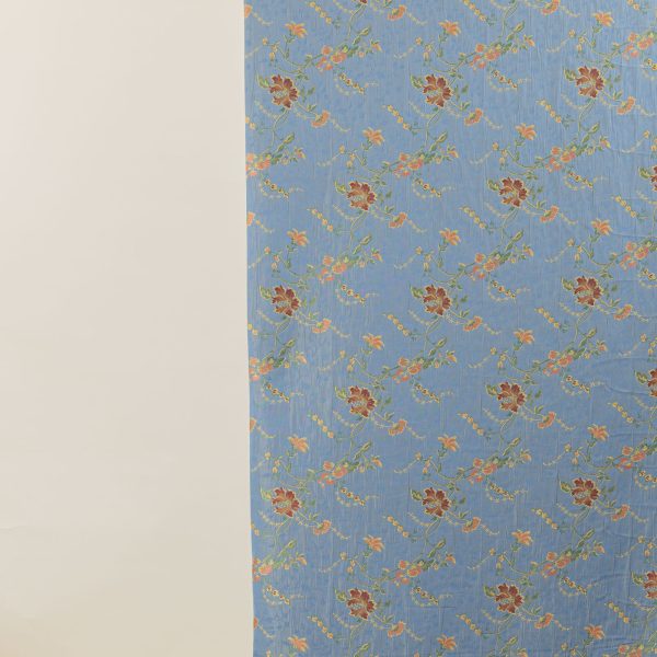 Lampasso fabric with light blue background and woven floral pattern in classic style. Flowers in shades of red, orange and yellow with green leaves, perfect for curtains, pillows, upholstery and shabby chic decorations. Elegant and vibrant print for decorating with personality. Made in Italy.