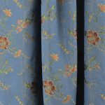 Lampasso fabric with light blue background and woven floral pattern in classic style. Flowers in shades of red, orange and yellow with green leaves, perfect for curtains, pillows, upholstery and shabby chic decorations. Elegant and vibrant print for decorating with personality. Made in Italy.