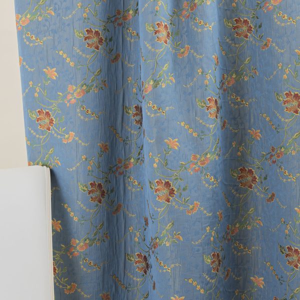 Lampasso fabric with light blue background and woven floral pattern in classic style. Flowers in shades of red, orange and yellow with green leaves, perfect for curtains, pillows, upholstery and shabby chic decorations. Elegant and vibrant print for decorating with personality. Made in Italy.