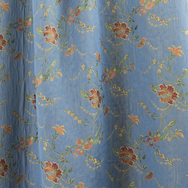 Lampasso fabric with light blue background and woven floral pattern in classic style. Flowers in shades of red, orange and yellow with green leaves, perfect for curtains, pillows, upholstery and shabby chic decorations. Elegant and vibrant print for decorating with personality. Made in Italy.